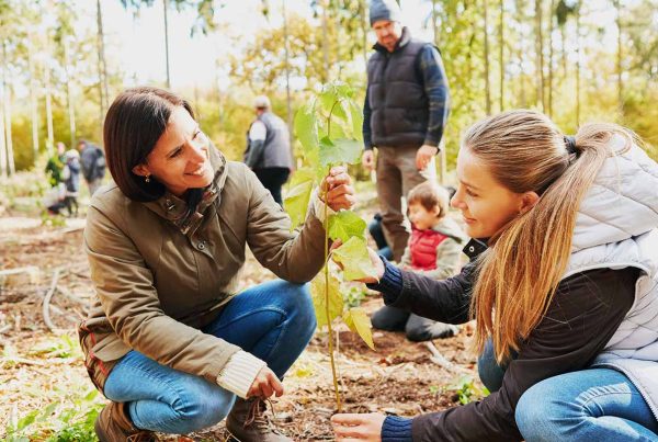 group of people planting trees. In the forefront there are two women doing the planting. Climate Action as an image